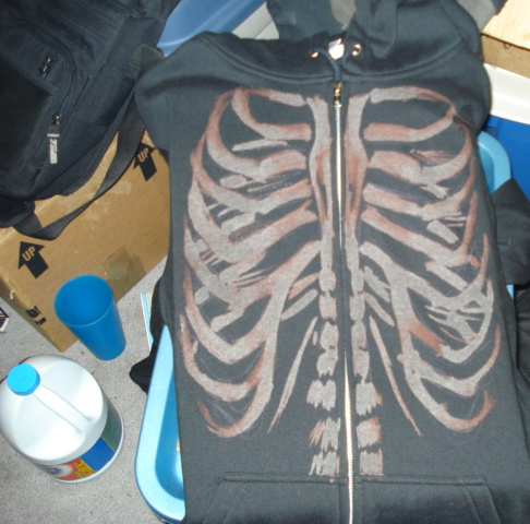 Black zip hoodie painted with a rib cage and spine across the front