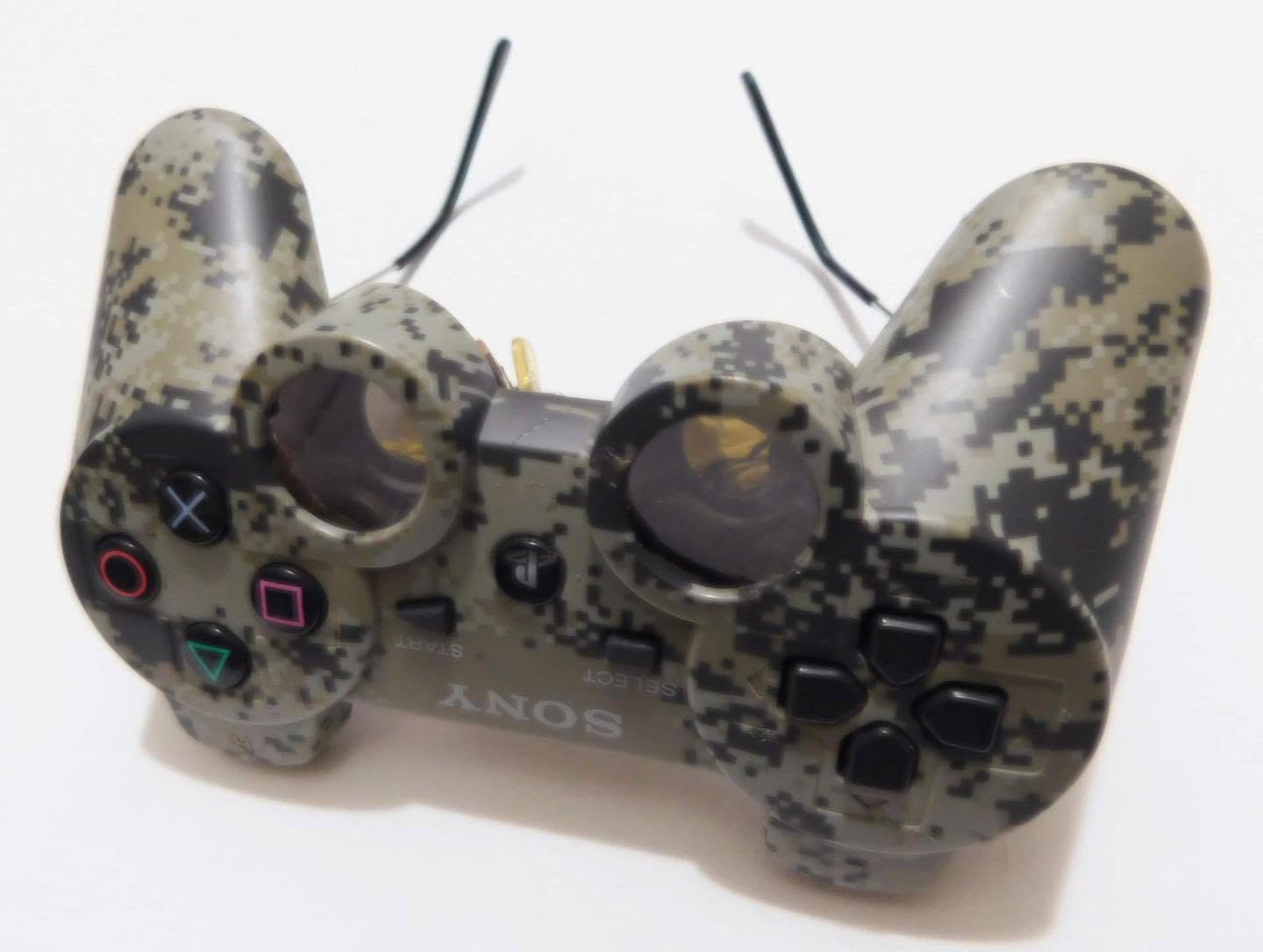 Angled white-background product photograph of camo PlayStation controller sunglasses